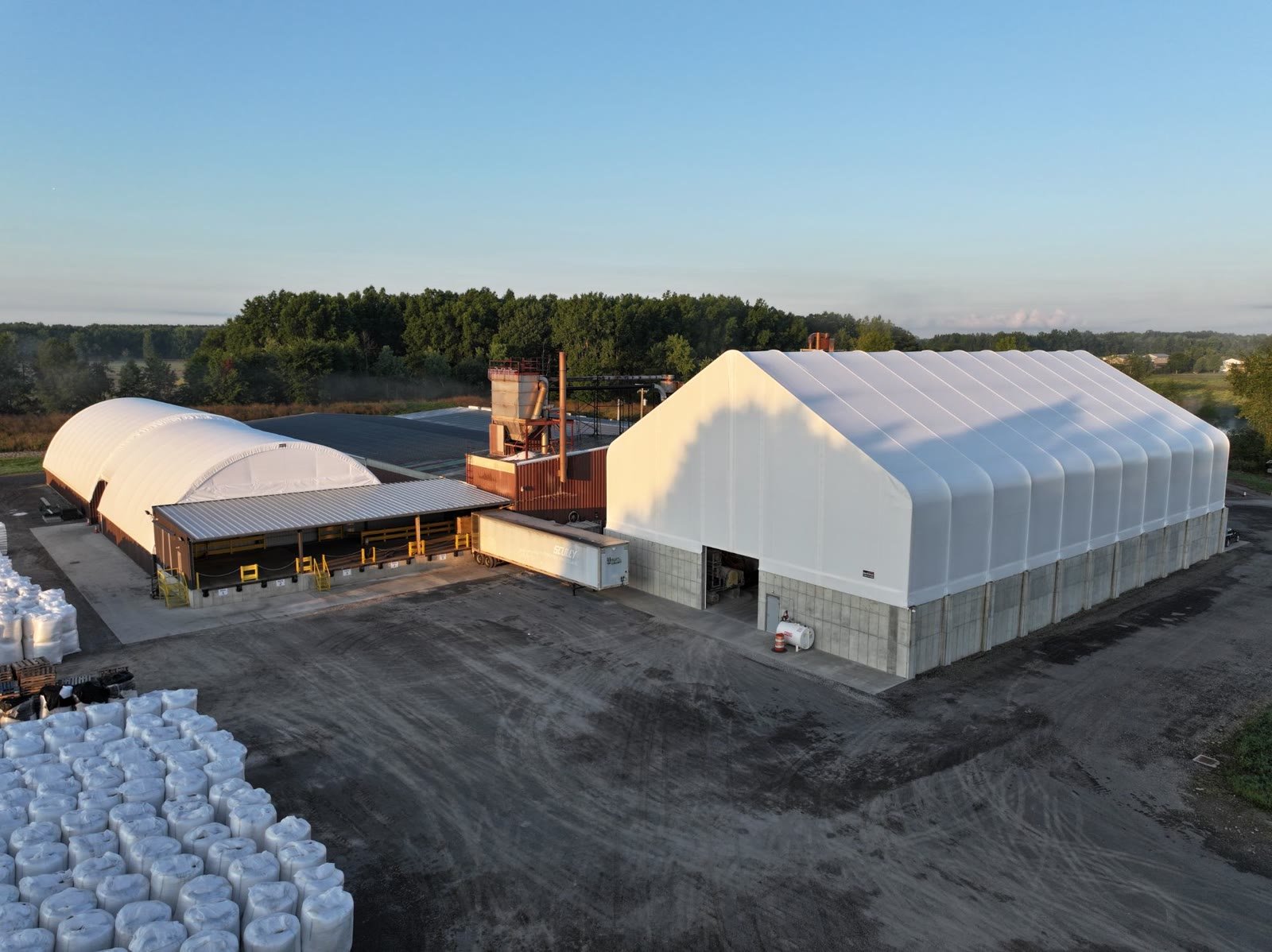 Aerial view of an industrial storage facility with fabric domes at sunrise